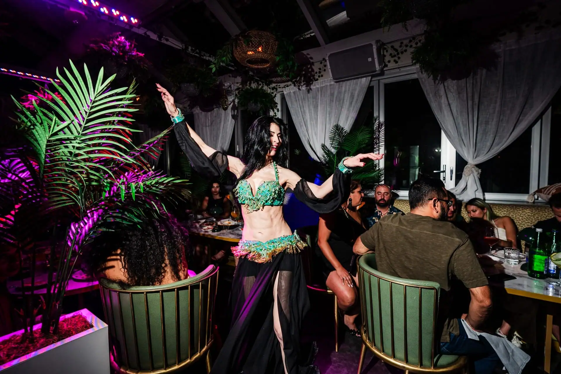 Belly dancer performing for guests in a lounge atmosphere.