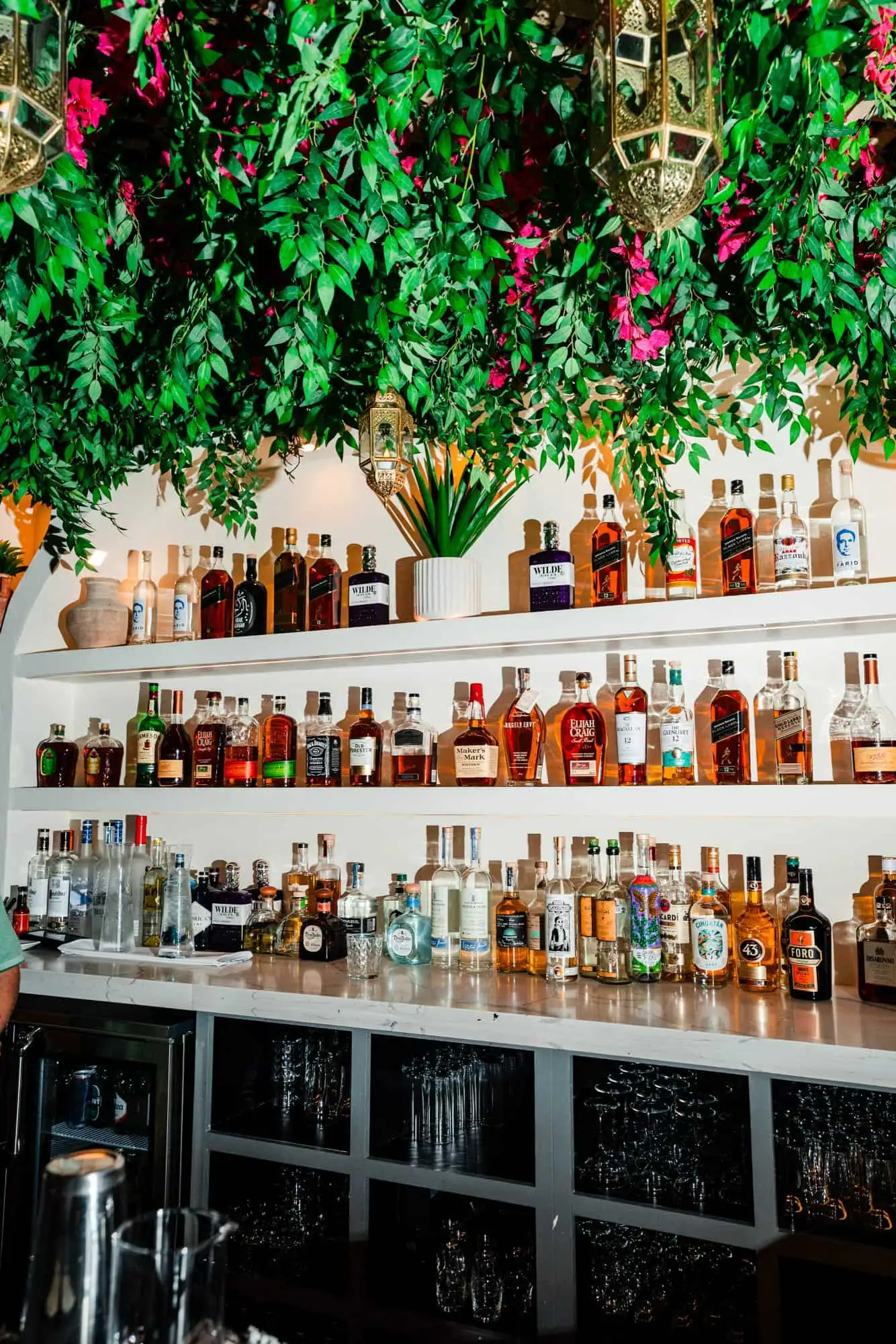 Backlit lounge bar shelves with bottles and warm ambient lighting.